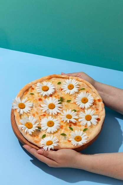 Mani ad alto angolo che tengono la pizza con i fiori