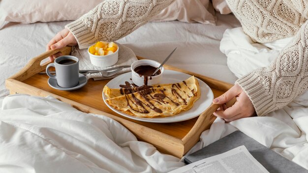 Mani ad alto angolo che tengono vassoio con colazione