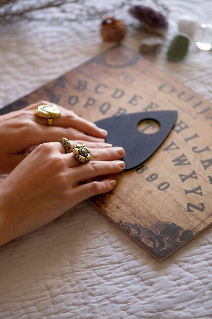 Mani ad alto angolo con tavola Ouija in legno