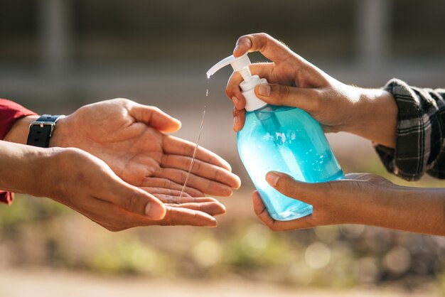 Mani al flacone di gel per lavarsi le mani e spremere gli altri per lavarsi le mani.