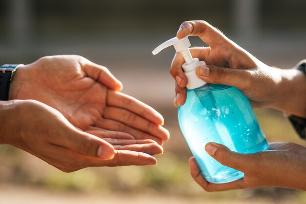 Mani al flacone di gel per lavarsi le mani e spremere gli altri per lavarsi le mani.