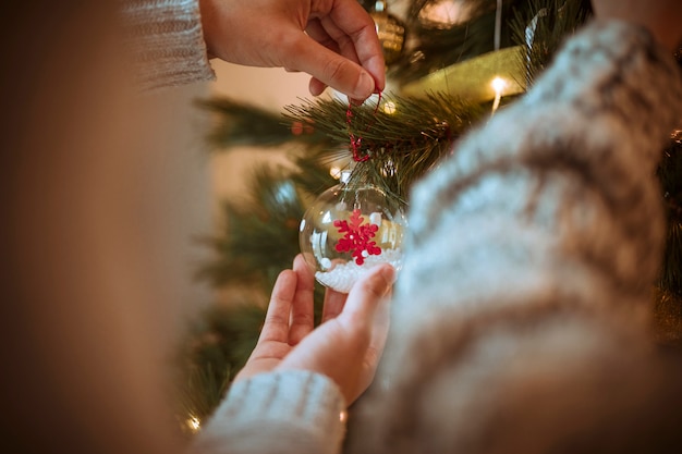 Mani che decorano l&#39;albero di Natale con le bagattelle