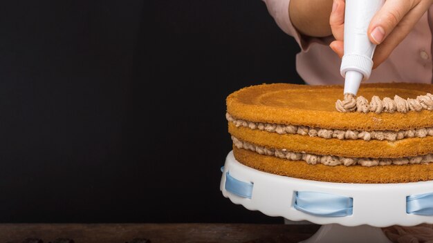 Mani che decorano la torta con lo spazio della copia