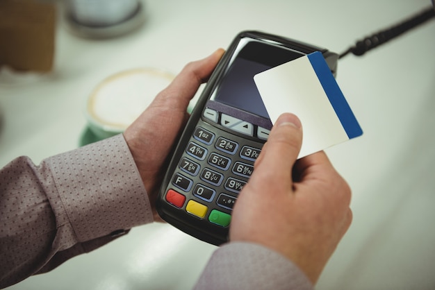 Mani che effettuano il pagamento tramite carta di credito nella caffetteria Mani che effettuano il pagamento tramite carta di credito nella caffetteria