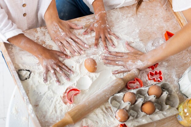 Mani che giocano nella farina accanto al rullo della cucina