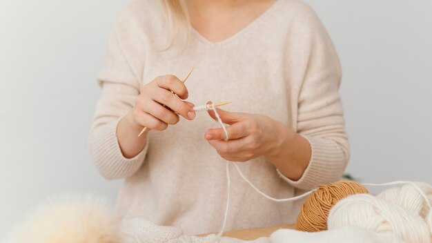 Mani che lavorano a maglia con il primo piano del filo bianco