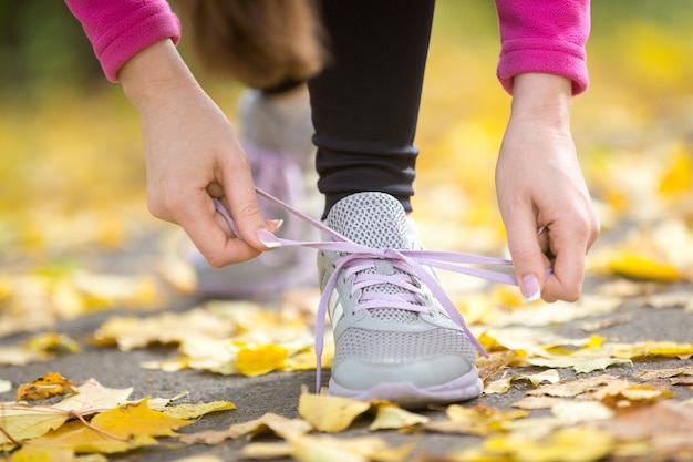 Mani che legano i calzoni dei formatori all&#39;aperto di autunno