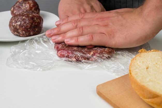 Mani che preparano carne per hamburger