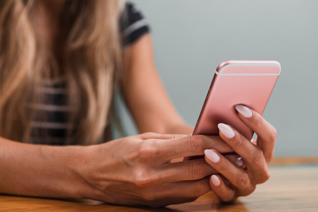 Mani che scrivono un messaggio sul telefono rosa