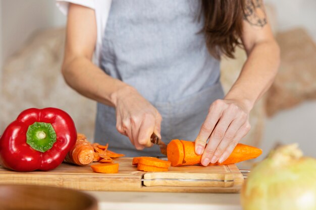 Mani che tagliano la carota da vicino