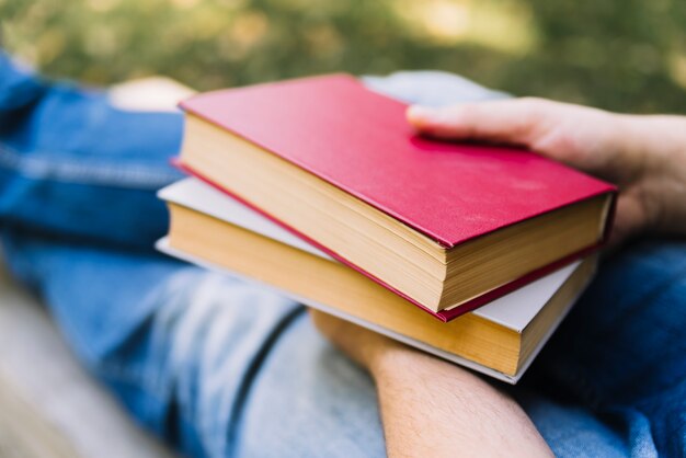 Mani che tengono i libri al parco