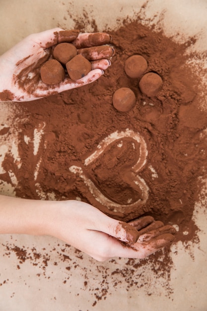 Mani che tengono i tartufi al cioccolato con la polvere di cacao