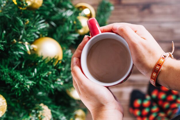 Mani che tengono la tazza di caffè all&#39;albero di Natale