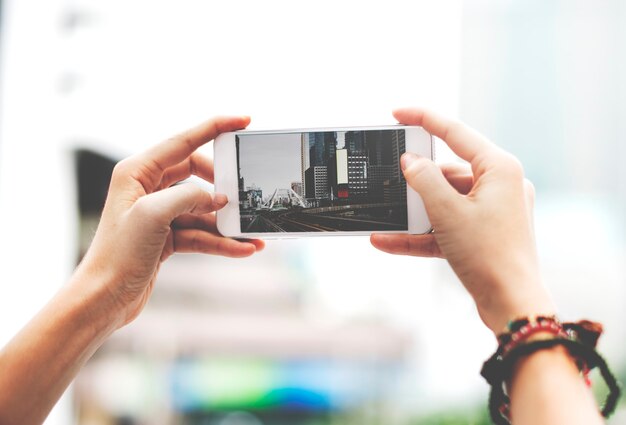 Mani che tengono lo schermo del telefono cellulare che mostra la foto di vista della città del paesaggio della metropolitana