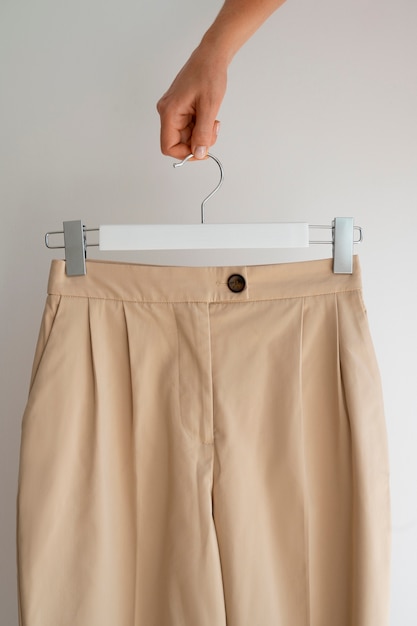 Mani che tengono pantaloni beige marrone chiaro