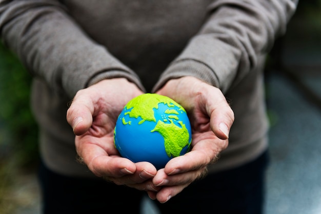 Mani che tengono un pianeta terra globo di argilla