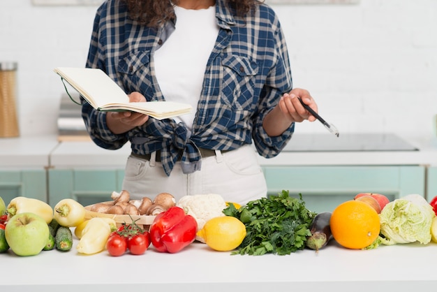 Mani che tengono un taccuino accanto alle verdure