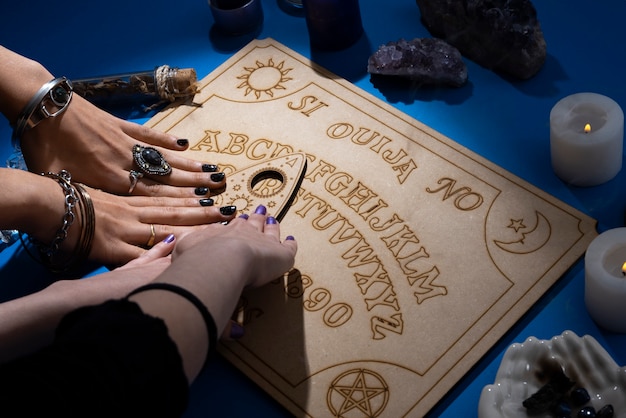 Mani che toccano la tavola di legno Ouija ad alto angolo