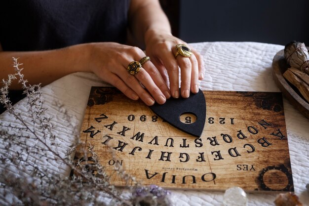 Mani che utilizzano la vecchia tavola di legno Ouija ad alto angolo