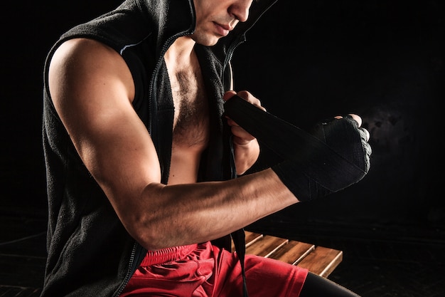 mani con benda di kickboxing di formazione uomo muscolare sul nero