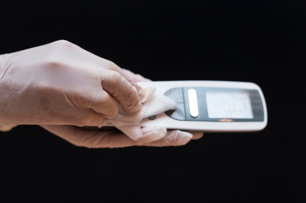 Mani con guanti che disinfettano il telefono