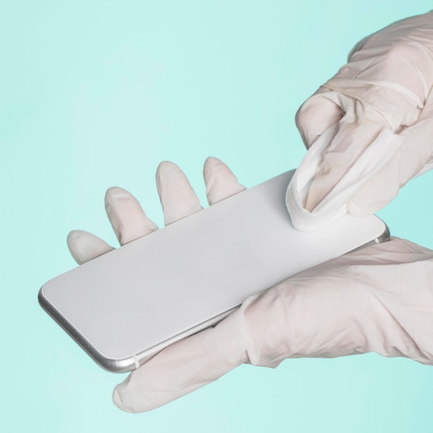 Mani con guanti chirurgici pulizia smartphone