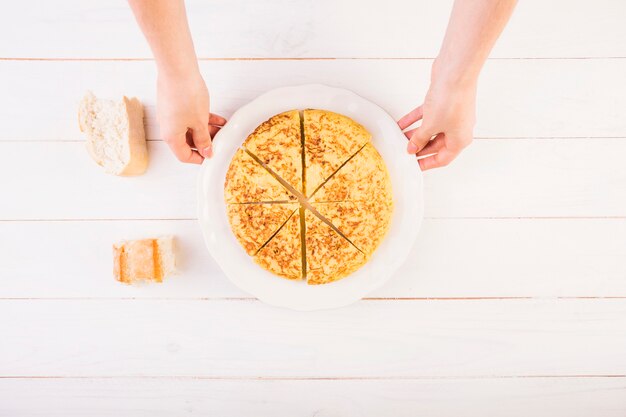 Mani con piatto torta sul tavolo della cucina