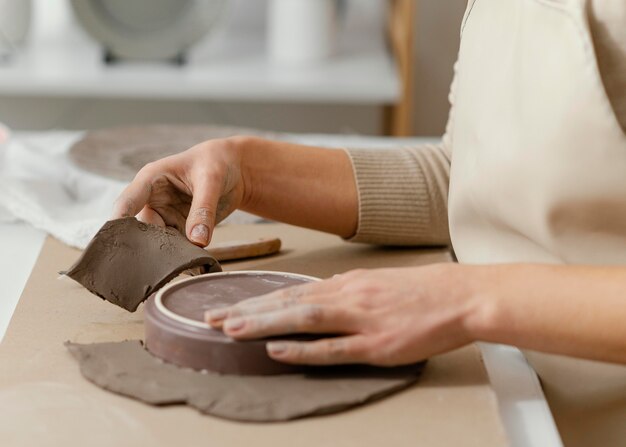 Mani del primo piano che fanno ceramiche