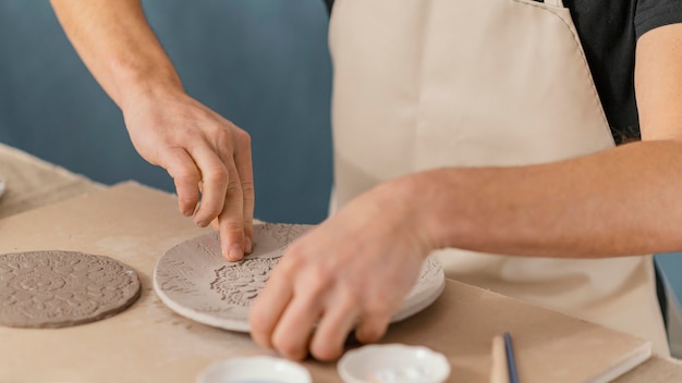 Mani del primo piano che fanno ceramiche