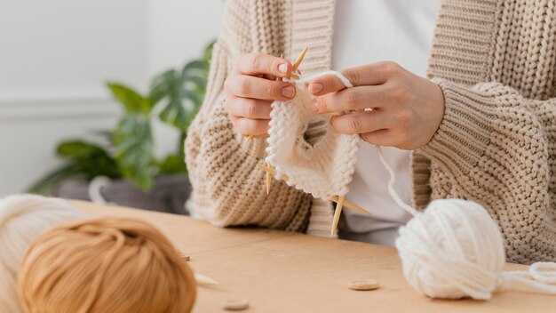 Mani del primo piano che lavorano a maglia con gli aghi