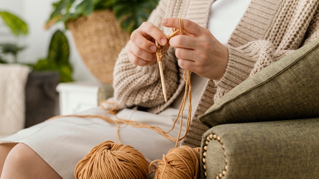 Mani del primo piano che lavorano a maglia con gli aghi