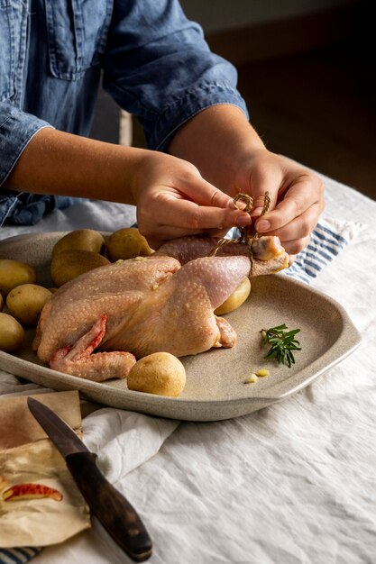 Mani del primo piano che legano le cosce di pollo