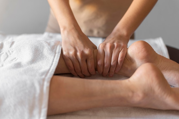 Mani del primo piano che massaggiano la gamba