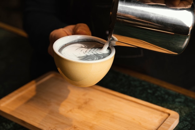 Mani del primo piano che preparano bevanda con latte