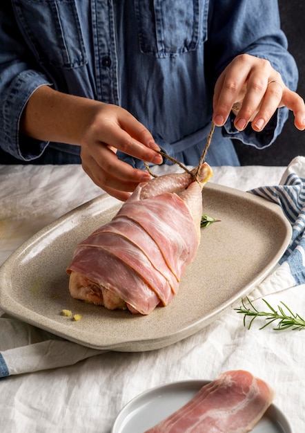 Mani del primo piano che preparano il pollo