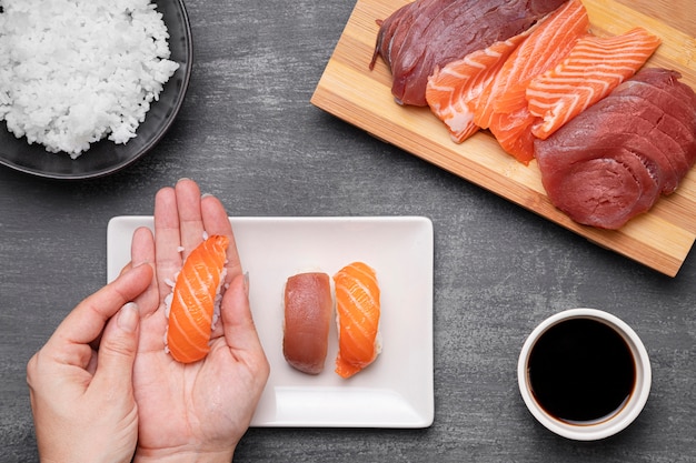 Mani del primo piano che preparano sushi