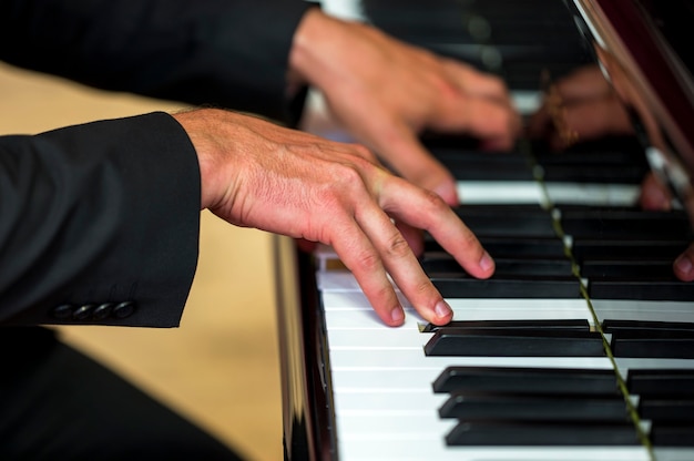 Mani del primo piano che tengono gli accordi sul pianoforte classico