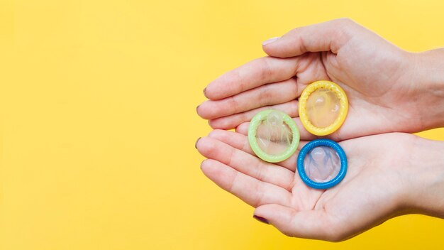 Mani del primo piano che tengono i preservativi con copia-spazio