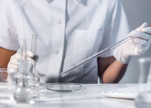 Mani del primo piano che tengono la vetreria di laboratorio