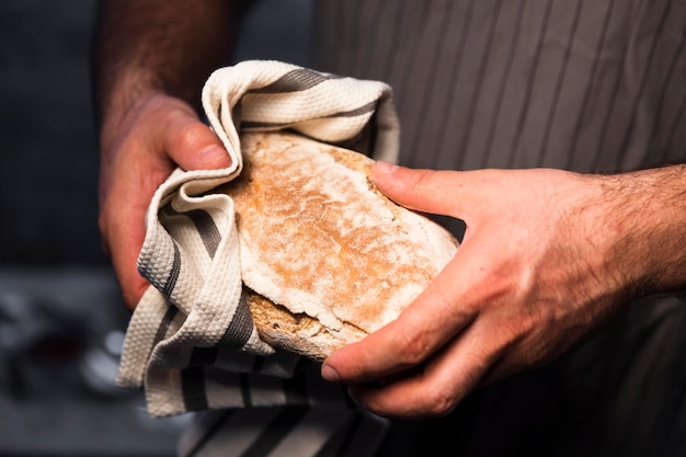 Mani del primo piano che tengono pane fatto in casa