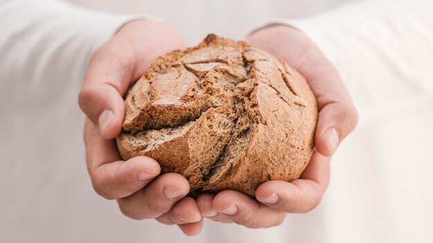 Mani del primo piano che tengono pane saporito