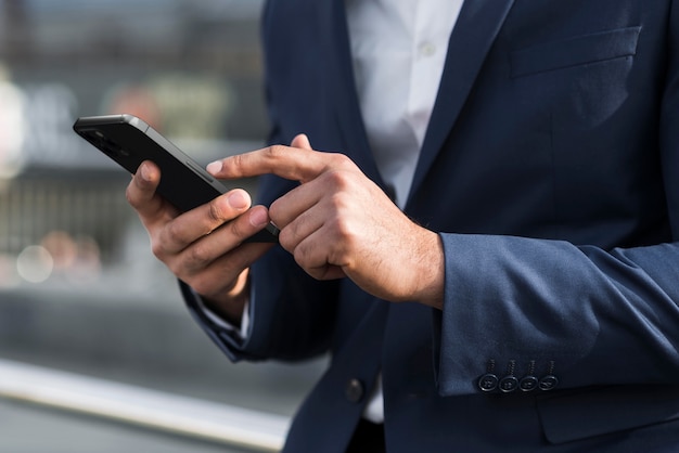 Mani del primo piano che tengono telefono