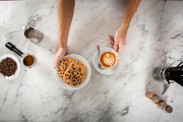 Mani dell'uomo con i biscotti e un cappuccino