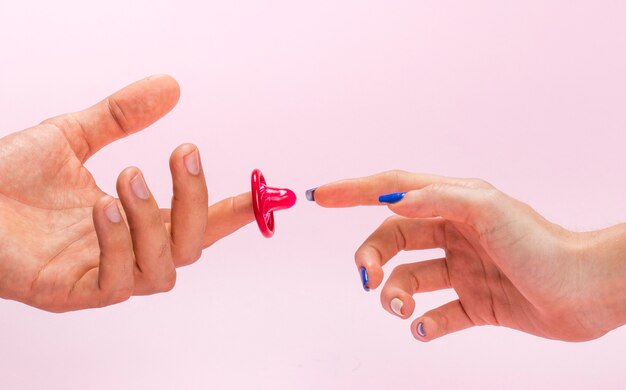 Mani dell'uomo e della donna del primo piano con il preservativo