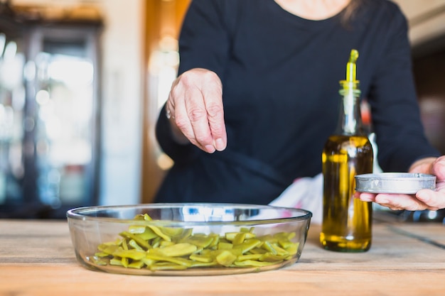 Mani della donna anziana che cucina nella cucina