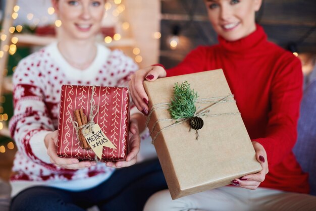 Mani della donna che danno i regali di Natale