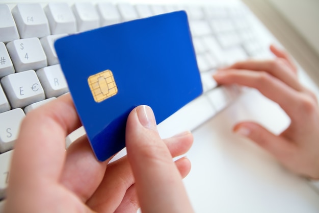 Mani della donna, computer portatile, carta di credito, pagamento in linea di acquisto