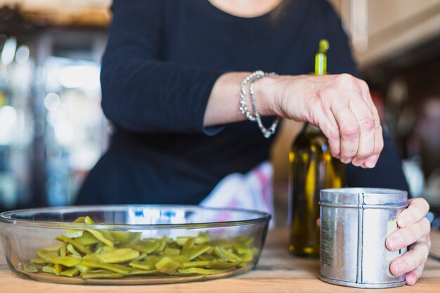 Mani della donna invecchiata che cucina nella cucina