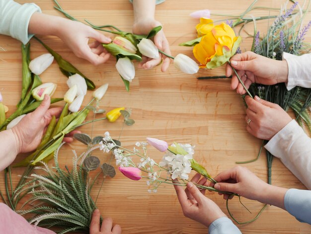 Mani delle donne di alta vista con i fiori di primavera
