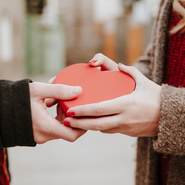 Mani di coppia con scatola a forma di cuore